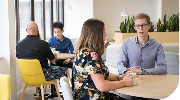 Mott MacDonald People - Female and male conversing around a table.