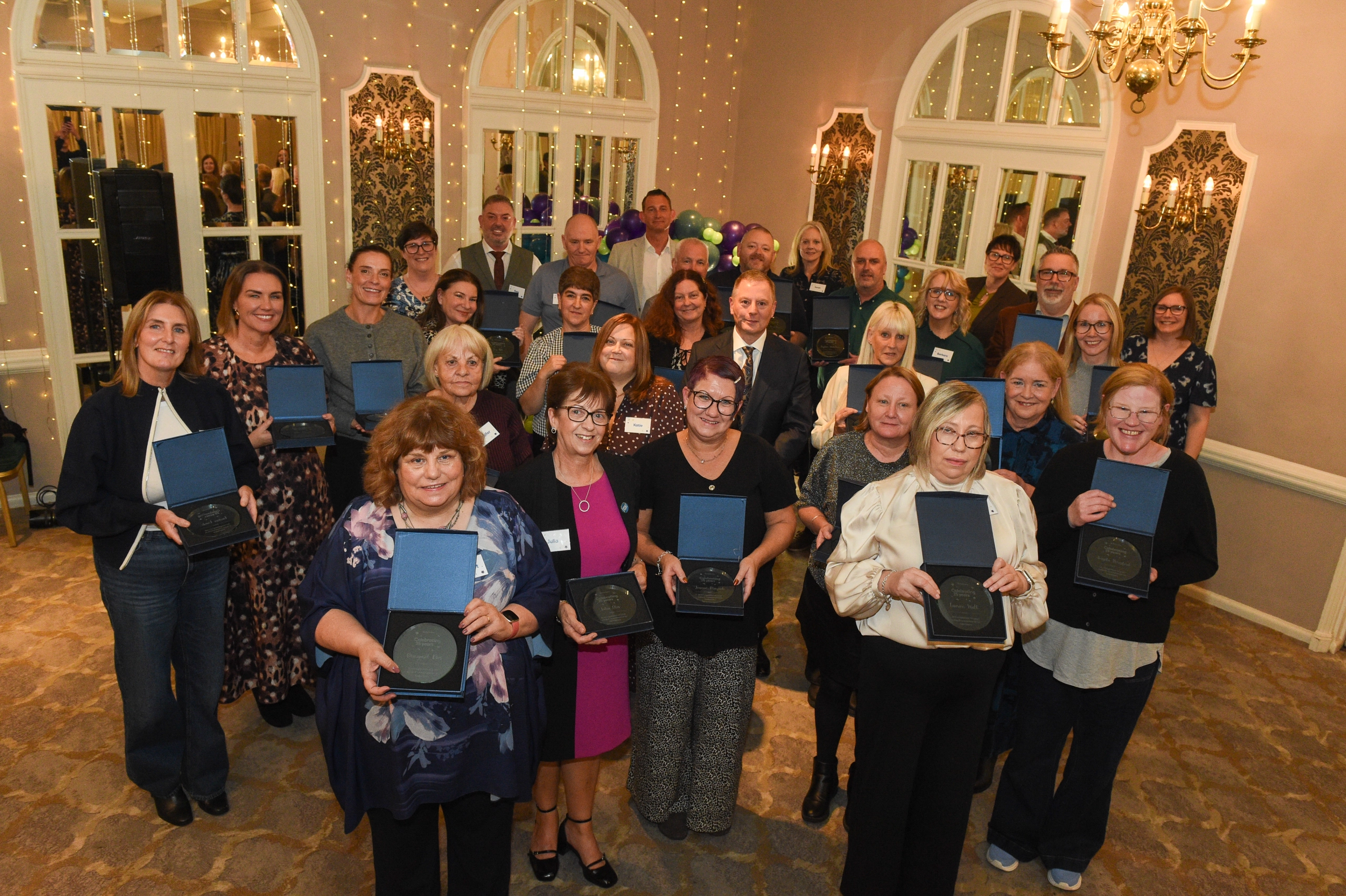 Sanctuary colleagues holding engraved glass plaques at their 25-year long service celebration