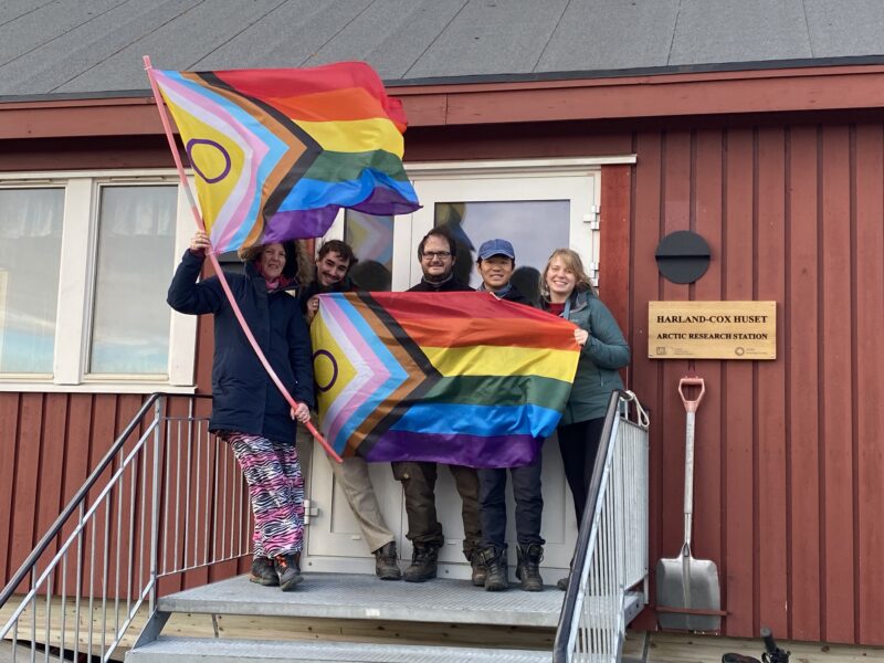 The team at Harland-Cox Huset, the UK Arctic Research Station, fly the progress pride flag (Photo Fran Pothecary)