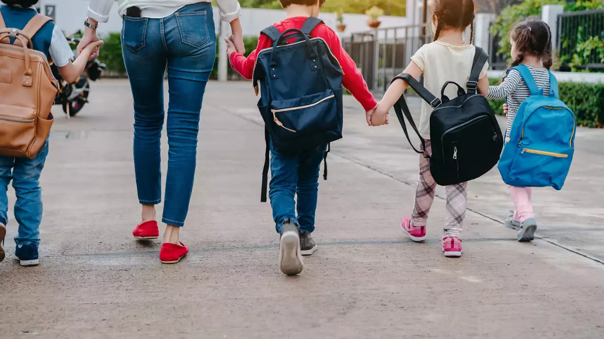 Back to school - children with parent walking in a line