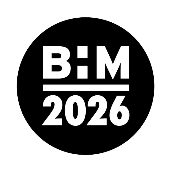 A high-contrast, circular graphic emblem featuring bold white typography set against a solid black disc, presented on a plain white background. The design is split into two tiers by a horizontal white line: Top section: Displays the acronym BHM in a heavy, stylised sans-serif typeface. The central letter H is creatively rendered as two vertically stacked rectangular blocks (similar in style to a thick colon), flanked by a blocky 'B' and 'M'. Bottom section: Features the year 2026 written in matching bold, clean white numerals. The visual style is minimalist and modern, commonly associated with the official branding and logos for Black History Month (BHM).