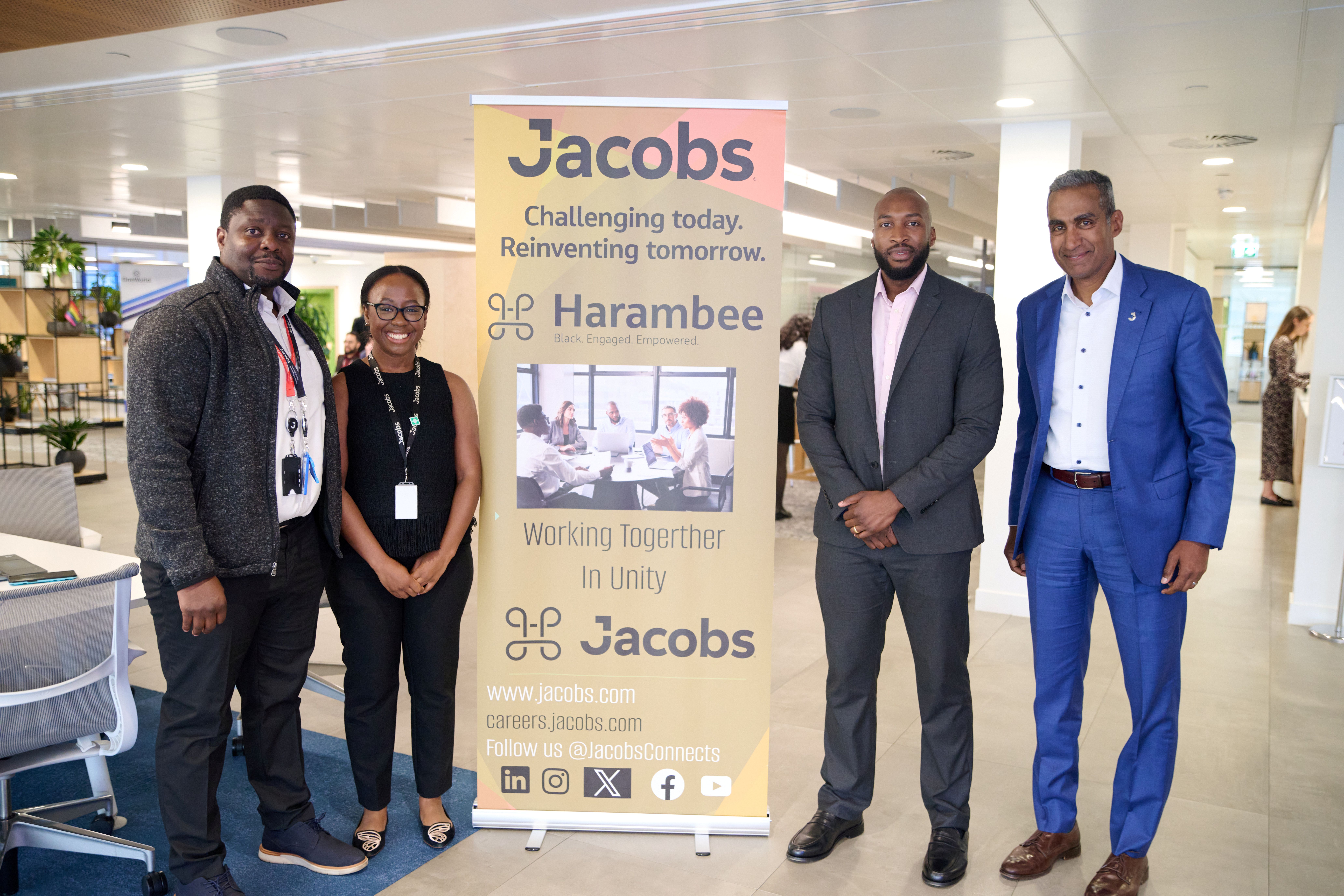 A group of mixed genders, african descent standing in front of a harambee poster