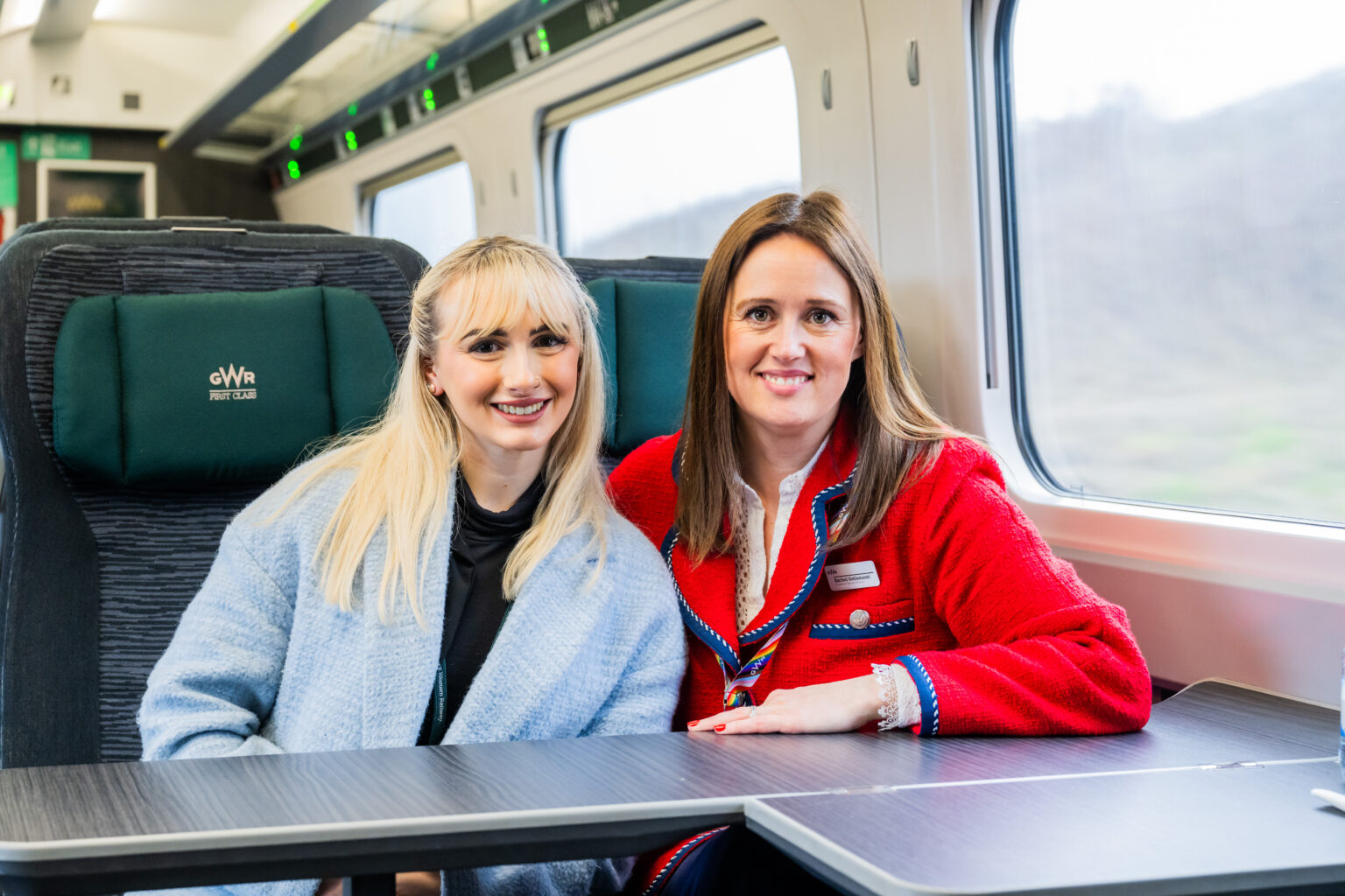 Two staff members pose together in a train
