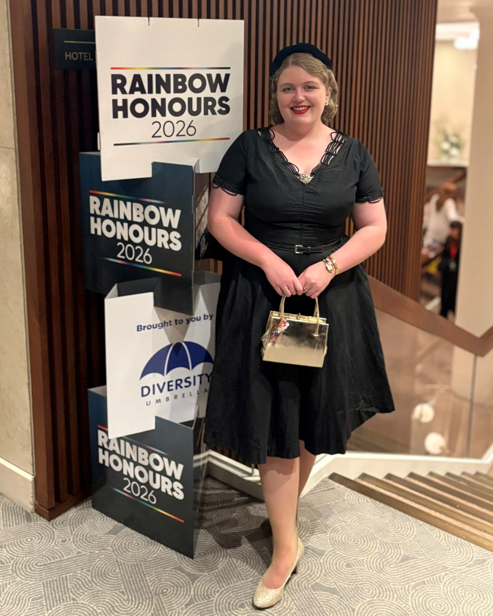 Lizzie standing in front of a Rainbow Honours b2026 anner