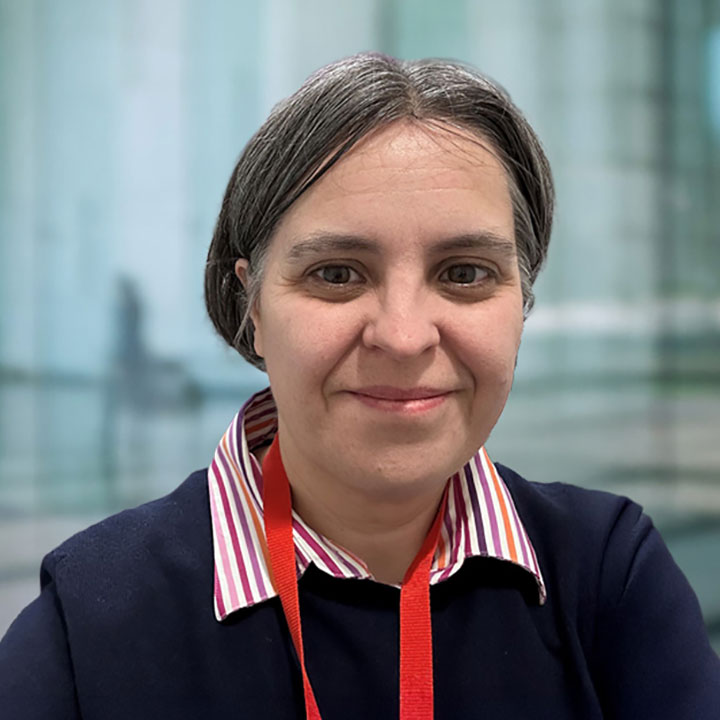 Catherine Treagus-Mullan a white woman with dark brown hair and brown eyes, wearing a red and white striped shirt and a blue cardigan
