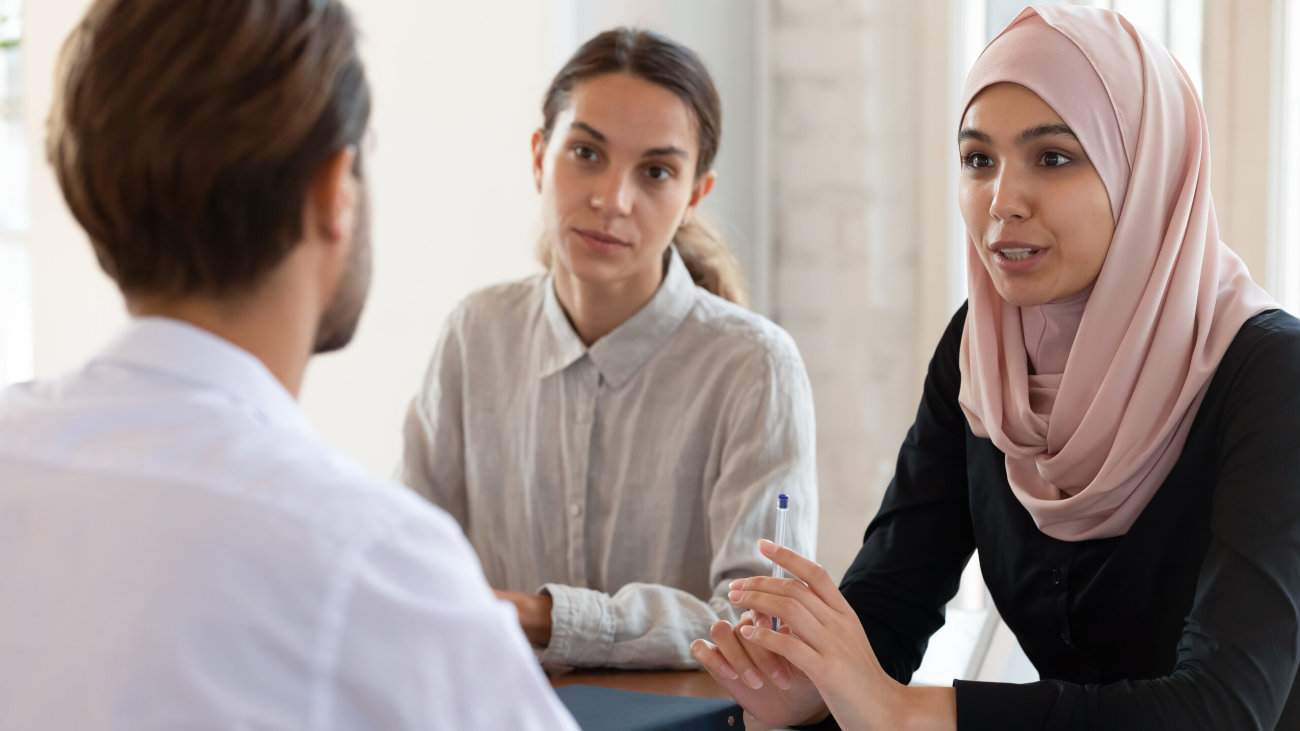 Two women, one in a hijab,  and a man 