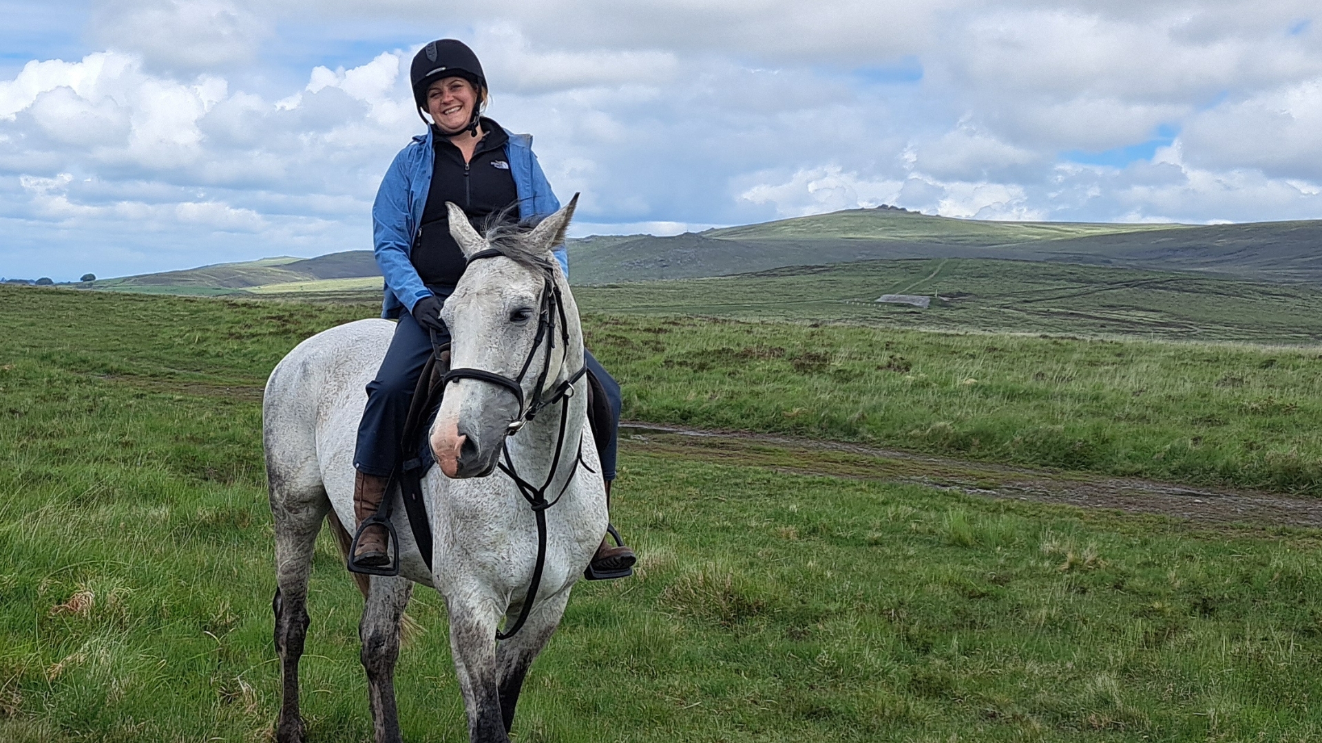 Ruth on a white hose wearing a riding hat and light blue sweater