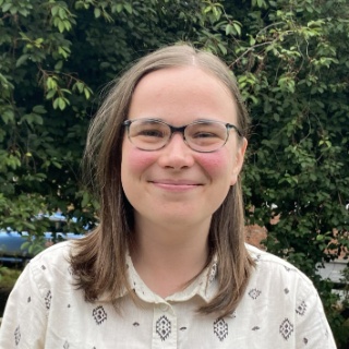 A women with blue framed glasses and straight light brown shoulder length hair