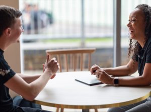 2 people sat at a table chatting and smiling