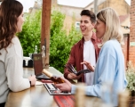 3 people stood at a bar with a laptop in front of them