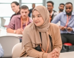 A Muslim woman in a hijab sitting behind a desk