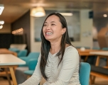 An East Asian woman smiling broadly in a office setting