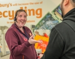 A white female employee smiling and conversing with a client at a till