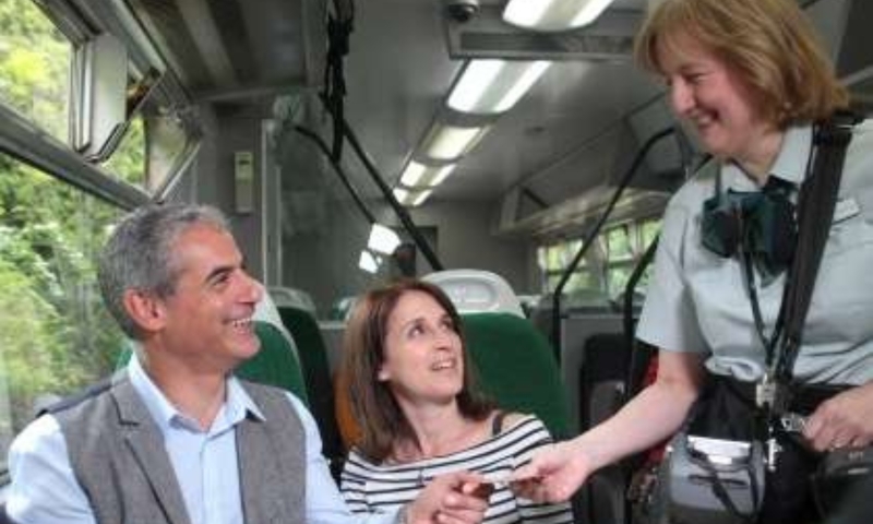 A train gaurd selling a ticket to passengers