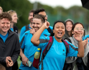 A diverse group of Mott Mac collegues in blue tshirts and backpacks