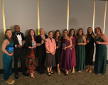 A group of diverse collegues posing with their awards, they are of different gender, age and ethnicity