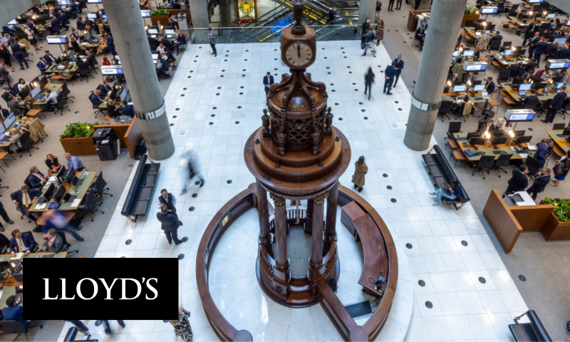 This image shows the Underwriting Room at Lloyd’s of London, capturing a high-angle view of a bustling, modern financial marketplace.