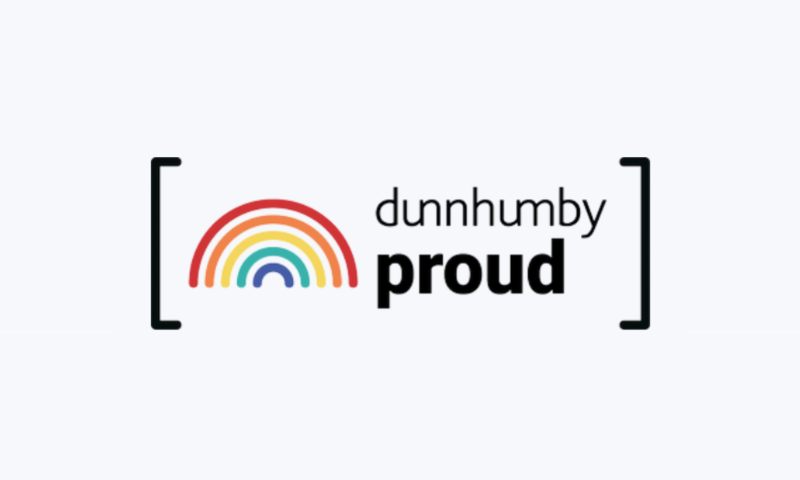 The Logo: The word "dunnhumby" is written in a thin, black sans-serif font, while the word "proud" sits directly beneath it in a bold, black typeface.  The Icon: To the left of the text is a stylized rainbow consisting of five concentric semi-circles in red, orange, yellow, teal, and purple.