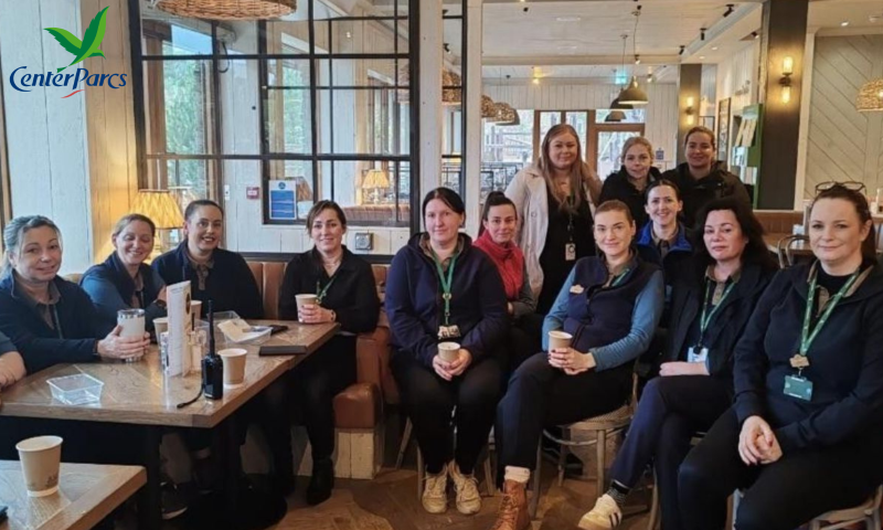 This image shows a group of approximately 13 women gathered in a bright, modern cafe or restaurant area, with a Center Parcs logo visible in the top left corner.