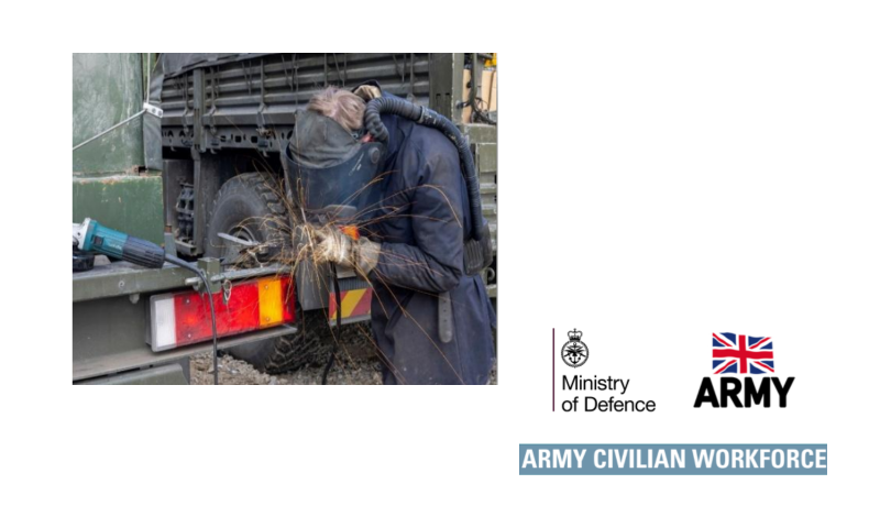 The image shows a person engaged in metalwork, likely grinding or cutting, on the back of a large military-style vehicle. The scene is filled with action and industrial detail.  Key Elements The Worker: A person wearing dark blue or black protective coveralls is leaning over a metal component. They are equipped with a welding helmet/face shield and heavy-duty gloves for protection against heat and sparks.  The Action: A shower of bright orange sparks is flying from the point of contact between a tool and the metal, indicating an abrasive process like grinding.  Equipment: * On the left, a teal and black angle grinder (likely a Makita brand based on the color and shape) rests on the edge of the vehicle bed.  The worker appears to be using a powered air-purifying respirator (PAPR) system, visible as a black corrugated hose connecting the back of their helmet to a battery pack on their waist.  The Vehicle: The work is being performed on the rear of a heavy-duty, olive-drab truck. Visible features include a large off-road tire, a metal tailgate, and a rectangular taillight assembly with red and amber sections.