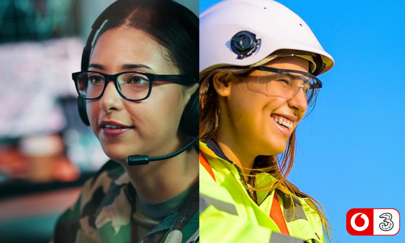 Left Side: Control or Operations Setting Person: A young woman with dark hair pulled back, wearing black-rimmed glasses and a headset with an attached microphone. She has a focused expression, looking slightly off-camera.  Clothing: She is wearing a camouflage pattern top or jacket.  Background: The background is softly blurred but appears to show an office or control room environment with computer screens.  Right Side: Field or Engineering Setting Person: A smiling young woman looking towards the right side of the frame.  Clothing & Gear: She is wearing a white safety helmet (hard hat), clear protective safety glasses, and a high-visibility yellow and orange jacket.  Background: A clear, vibrant blue sky, suggesting she is working outdoors.  Branding In the bottom right corner, there is a small white badge with a red border containing two logos side by side: the Vodafone speech mark logo and the Three (3) network logo.