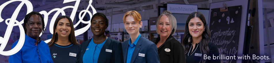 This wide banner image features a group of diverse retail and pharmacy staff against a retail background, framed with branding elements:  People featured (left to right):  A man with dreadlocks wearing a bright blue button-down shirt.  A smiling woman with long brown hair in a dark blue top with light blue trim and a Boots badge.  A Black woman with her hair tied back, wearing a bright blue top layered under a dark blazer with a name badge.  A young man with short reddish-orange hair wearing a bright blue shirt and a matching dark blazer.  A woman with silver-grey hair tied up, wearing a black jacket with a name tag.  A woman with long dark wavy hair wearing a black collared top and name badge.  Branding & Layout:  Top Left: A large, stylized white cursive Boots logo overlaps the background.  Bottom Right: White text reads "Be brilliant with Boots."  Background: The background shows a softly blurred retail environment with signage (such as a "bareMinerals" display) and a blackboard menu, overlaid with a cool blue-purple gradient effect.