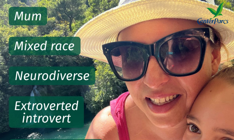 The image shows a close-up, outdoor self-portrait featuring a woman wearing a light-coloured woven straw hat and large dark sunglasses, smiling warmly alongside a child whose face is partially visible in the bottom-right corner. The background features lush green foliage, trees, and a turquoise body of water.   On the top-right corner, there is a logo for Center Parcs with a green bird icon.   On the left side, four dark green text boxes display white italicised labels:   Mum   Mixed race   Neurodiverse   Extroverted introvert